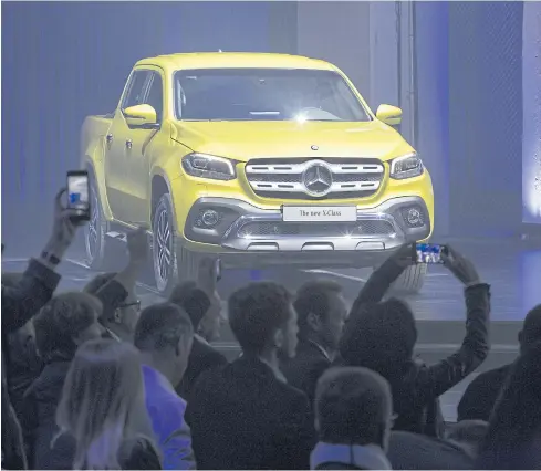  ?? BLOOMBERG ?? Attendees use mobile phones to take photograph­s of an X-Class pickup truck on display during a launch event in Cape Town, South Africa on Tuesday.
