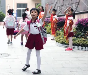  ??  ?? 北京市西城区奋斗小学，一年级新生向校门外的­妈妈挥手告别