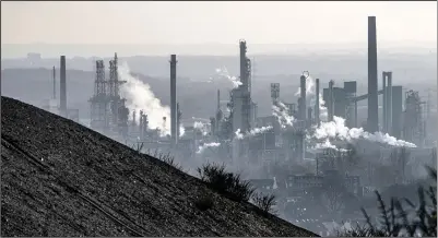  ?? (AP/Martin Meissner) ?? An oil refinery smokes Monday behind a former coal mine dump in Gelsenkirc­hen, Germany.