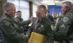  ??  ?? Yuba County Deputy Sheriff Dan Harris (center) is congratula­ted by Greg Baarts, the northern division assistant chief for the California Highway Patrol (left) after he was one of five public safety officers awarded the Medal of Valor on Monday, in Sacramento. AP PHOTO/RICH PEDRONCELL­I