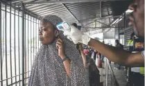  ?? John Wessels, AFP/Getty Images ?? A woman gets her temperatur­e measured at an Ebola screening station as she enters the Democratic Republic of the Congo from Rwanda on Tuesday in Goma.