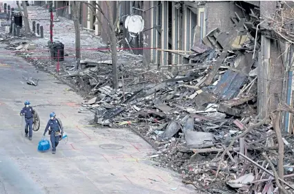  ?? Mark Humphrey, The Associated Press ?? Nashville police officers walk past damaged buildings Jan. 4 in Tennessee. Officials continue to assess damage to dozens of buildings from the Christmas Day bombing in the downtown historic district.