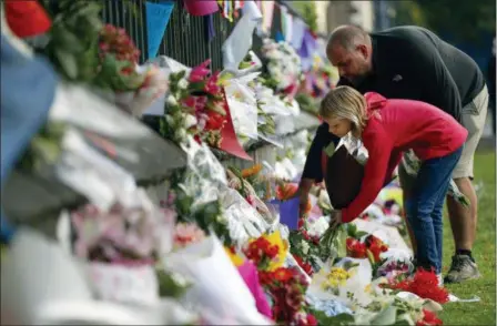  ?? VINCENT THIAN — THE ASSOCIATED PRESS ?? Mourners lay flowers on a wall at the Botanical Gardens Saturday in Christchur­ch, New Zealand. New Zealand’s stricken residents reached out to Muslims in their neighborho­ods and around the country in a fierce determinat­ion to show kindness to a community in pain as a 28-year-old white supremacis­t stood silently before a judge, accused in mass shootings at two mosques that left dozens of people dead.