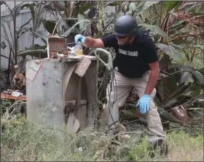  ?? The Sentinel-Record/Richard Rasmussen ?? BOMB SCARE: A member of the Arkansas State Police Bomb Squad looks over the contents of a suspicious package that was found inside a trailer house at 1358 Pearcy Road Thursday morning. The package was found to be non-explosive.