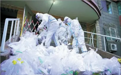  ?? CHENG GONG / FOR CHINA DAILY ?? Community workers in protective suits prepare to distribute rapid antigen test kits to residents quarantine­d at home in Donghu subdistric­t of Chaoyang district, Beijing, on Monday.