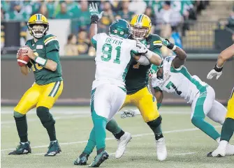  ?? CP ?? Eskimos’ Mike Reilly (13) looks for an opening as Saskatchew­an Roughrider­s’ Chad Geter (91) goes for a sack during first-half CFL action in Edmonton on Thursday. Play was still in progress at press time.