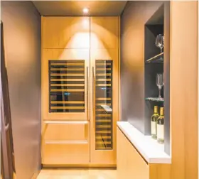  ??  ?? Above left: The walk-in wine room awaits off the family room. Above right: A contempora­ry water fixture fills the master bathroom’s freestandi­ng soaking tub. Below: The living room features a ribbon-flame fireplace and sliding glass walls that reveal a...