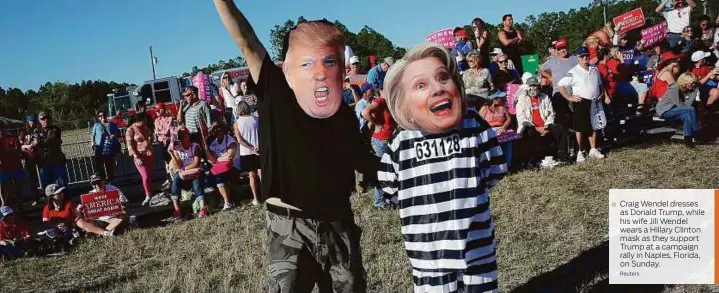  ??  ?? Craig Wendel dresses as Donald Trump, while his wife Jill Wendel wears a Hillary Clinton mask as they support Trump at a campaign rally in Naples, Florida, on Sunday.