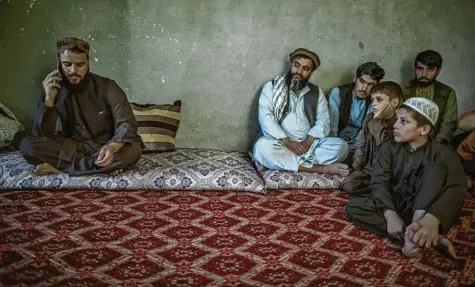 ?? Foto: Oliver Weiken, dpa ?? Afghanisch­e Kinder und andere Taliban beobachten Matiullah Ruhani, den Sprecher der Taliban für Kundus, während er ein Telefonat führt.