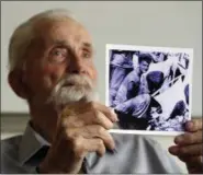  ?? DON RYAN — THE ASSOCIATED PRESS ?? In this Monday photo, WWII veteran Marvin Strombo holds up a photo of himself taken during the battle on Saipan with him holding a captured sword and flag in Portland, Ore.