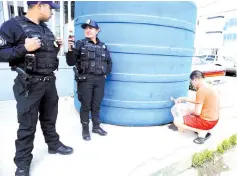  ?? — AFP photo ?? Police officers stand guard near a drinking water tank, installed to supply local residents, during a running water cut off due to maintenanc­e tasks in Mexico City.