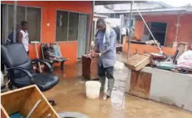  ??  ?? ACCRA: This file photo shows a man scooping water from his flooded office, two days following heavy flooding and fire at a filling station.