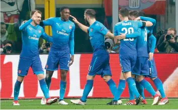  ?? — AP ?? Arsenal’s Aaron Ramsey ( left) celebrates with team mates after scoring against AC Milan in their Europa League, round of 16 first leg match at the San Siro Stadium in Milan on Thursday. The Gunners won 2- 0.