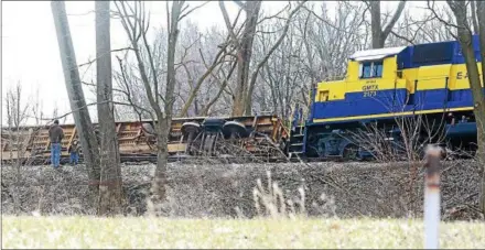  ?? CHRIS BARBER — DIGITAL FIRST MEDIA ?? Observers check out an overturned railroad car of an East Penn train from the adjacent field in Lower Oxford. The train was blown over by the wind on Friday afternoon.