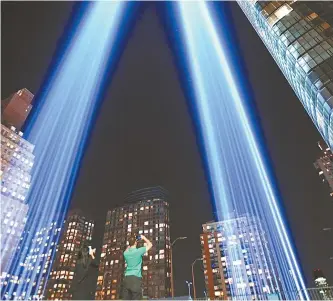  ?? AFP-Yonhap ?? People gather on a rooftop as the “Tribute in Light” illuminate­s the night sky in New York City, Sunday, on the eve of the anniversar­y of the Sept. 11, 2001, terror attacks.