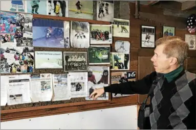  ?? LINDSAY MORAN — FOR THE RECORD ?? Dave Randall looks over a bulletin board with photos and stories about players he has coached over the past 40years on the homemade rink his father built outside the family home on Oakwood Avenue in Troy. Dave Randall has coached hockey for 40years on...