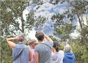  ?? TREVOR HUGHES/USA TODAY ?? Tourists gather to snap photos of an eruption Tuesday that sent a column of ash more than 2 miles above Kilauea volcano.