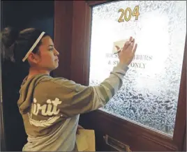  ?? AP PHOTO ?? Diana Hodges places a sticky note that calls for freeing 22-year old Daniela Vargas, a Argentine native who has lived in the United States since she was seven years old, on the office doors of lawmakers at the Capitol in Jackson, Miss.