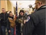  ?? (AP/Manuel Balce Ceneta) ?? Kevin Seefried (second from left) holds a Confederat­e battle flag as he and other insurrecti­onists are confronted by U.S. Capitol Police officers outside the Senate Chamber inside the Capitol in Washington, Jan. 6, 2021.