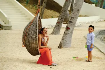  ??  ?? RESORT guest relaxes on the basket swing at the beach.