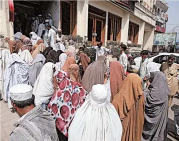  ?? MUHAMMAD SAJJAD/AP ?? Pakistanis wait outside a bank to receive cash under a government program for families in need Monday in Peshawar.