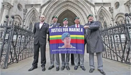  ??  ?? LONDON: This file photo taken on December 16, 2016 shows supporters posing for a photograph with a placard showing the Royal Marine flag with a picture of former Marine Sgt Alexander Blackman, outside the Royal Courts of Justice. — AFP