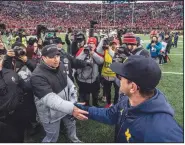  ?? AP/TONY DING ?? Ohio State head coach Ryan Day (front left) shakes hands with Michigan head coach Jim Harbaugh, front right, after an NCAA college football game in Ann Arbor, Mich., on Saturday.