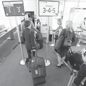  ?? 2013 PHOTO BY M. SPENCER GREEN, AP ?? Passengers and flight crew wait their turn at a United Airlines gate at O'Hare Internatio­nal Airport in Chicago. United uses a five- lane system similar to the one Delta is now testing.