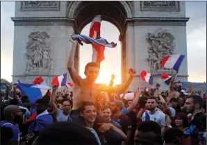  ?? (File Photo/AP/Thibault Camus) ?? People gather around the Arc de Triomphe in Paris to celebrate France’s World Cup victory over Croatia on July 15. A photo of a blond woman with a flag atop the Arc de Triomphe is circulatin­g online, incorrectl­y asserting it shows recent protests in Paris over the government’s latest coronaviru­s measures. But the photo shows celebratio­ns in Paris in July 2018 after France won the World Cup, not a recent protest.