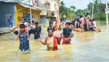  ?? — PTI ?? People shift to safe places from a flooded locality after heavy downpour, in Agartala on Sunday. Two persons were killed on Sunday in landslides triggered by incessant rains in Tripura with flash floods inundating several areas in four districts....