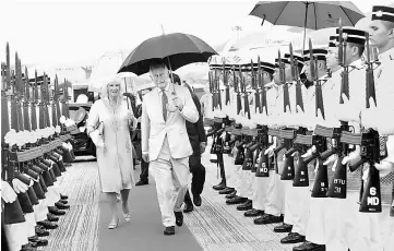 ??  ?? Their Royal Highnesses walking between the guard-of-honour mounted by military personnel from the 6th Battalion Royal Malay Regiment before departing for India from the Penang Internatio­nal Airport yesterday. — Bernama photo