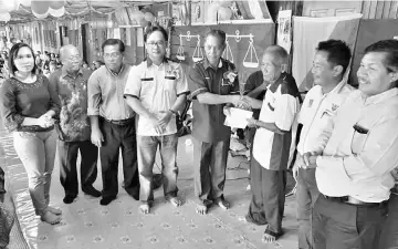  ??  ?? Penguang (fourth right) presents a cheque for RM35,000 to longhouse chieftain Mathias. On Penguang’s right is Alexander.