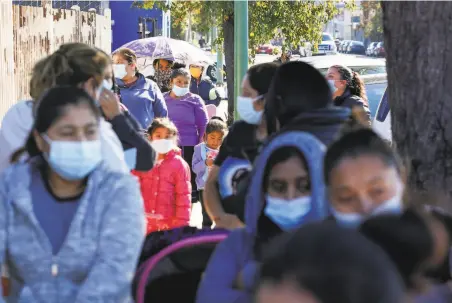  ?? Photos by Amy Osborne / Special to The Chronicle ?? Families wait in line at East Oakland Collective to receive nonperisha­bles and, for those that requested, a Thanksgivi­ng dinner.