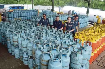  ??  ?? ISKANDAR (tengah) bersama pegawainya memeriksa gas yang dirampas di Jalan Papan, Pelabuhan Klang.