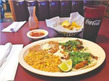  ?? PHOTO BY JIM TANNER ?? Two Mexico City-style tacos filled with pork are served with refried beans and a side of Mexican rice in a $5.99 special at La Altena.