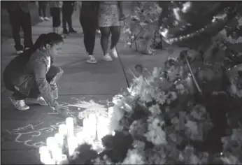  ?? Tribune News Service ?? A woman writes a message in chalk at a makeshift memorial outside Tops market on May 15, 2022, in Buffalo, New York. A gunman opened fire at the store the day before, killing 10 people.