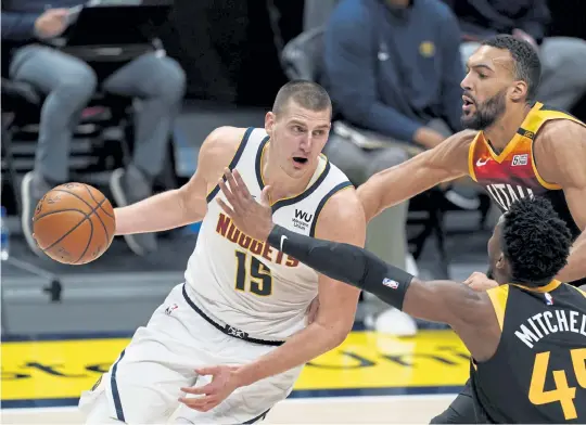  ?? David Zalubowski, The Associated Press ?? Nuggets center Nikola Jokic, left, drives to the basket as Jazz guard Donovan Mitchell, front right, and center Rudy Gobert defend him in the second half Sunday in Denver. Jokic had 47 points in Denver’s 128-117 victory.