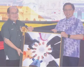 ?? ?? Uggah (left) presents a memento as a token of appreciati­on to Abang Johari.