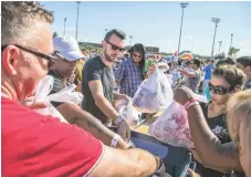  ?? PATRICK BREEN/ THE REPUBLIC ?? Volunteers from the Arizona Community Foundation place bags of food in a bin. The volunteers at the Tempe event broke a record for number of bags filled with food for kids within three minutes.