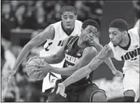  ?? The Associated Press ?? DOUBLE COVERAGE: Iowa’s Roy Devyn Marble, right, swipes at the ball while double- teaming Michigan’s Derrick Walton Jr., center, with Melsahn Basabe, left, during the Hawkeyes’ 85- 67 win on Saturday in Iowa City, Iowa. Marble scored 26 points in the...