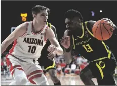  ?? RICK SCUTERI/AP ?? OREGON FORWARD QUINCY GUERRIER (13) drives against Arizona forward Azuolas Tubelis during the first half on Thursday in Tucson, Ariz.