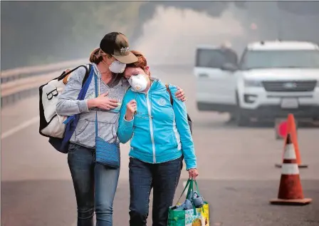  ?? RANDY PENCH/SACRAMENTO BEE VIA AP ?? Above, Colby Clark of San Francisco, left, comforts her mother, Bonnie Trexler, after being escorted by law enforcemen­t to her home in Silverado Highland to retrieve medicine and some personal items on Wednesday in Napa, Calif. Trexler was one of the...