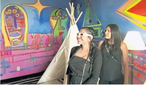  ??  ?? Kalene Thompson, left, views an installati­on art piece by contempora­ry Native American artist Ishkoten Dougi through 3D glasses at the Nativo Lodge .