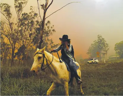  ?? RIDING TO SAFETY: Rhonda Anderson and her horse flee the flames near Mount Larcom. ??