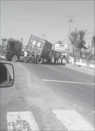  ?? (Zoisa Fraser photo) ?? This container truck caused a disruption to the rush hour traffic along the East Bank corridor at First Street, Mc Doom in the vicinity of the Shell Service Station yesterday afternoon, when its driver reportedly attempted to make a right turn. In the process of turning, the container became detached from its bed and was left in a tilted position. Despite the truck taking up two lanes and partially blocking traffickin­g on the other side of the road, drivers travelling in both directions could be seen jostling each other to get past the truck. Stabroek News was informed that the truck was safely remove sometime later