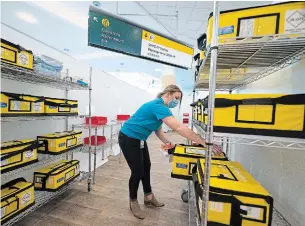  ?? JONATHAN HAYWARD THE CANADIAN PRESS ?? A LifeLabs employee helps set up a screening centre at Vancouver Internatio­nal Airport Friday. The centre is being set up to allow for new testing requiremen­ts coming into effect Sunday.