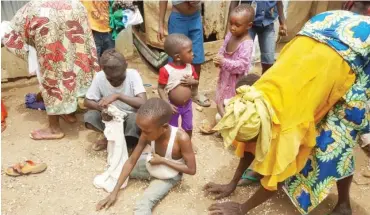  ??  ?? Women and children picking spilled beans at New Kuchingoro internally displaced persons camp, Abuja. PHOTO: