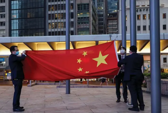  ?? ?? ► Funcionari­os bajan la bandera nacional china en el Distrito Financiero Central, en Hong Kong, el 15 de marzo de 2024.