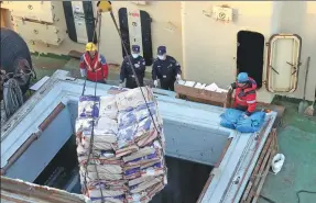  ?? ?? Left: Policemen conduct a border inspection at a port in Dalian on Feb 13. Right: Zhang Sheng (second from right) and Zhang Xin check bags of frozen fish on a Russian vessel on Feb 13 in Dalian.