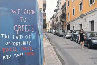  ?? LOUISA GOULIAMAKI, AFP/GETTY IMAGES ?? A slogan on a wall in Athens in May complains about austerity measures in Greece.